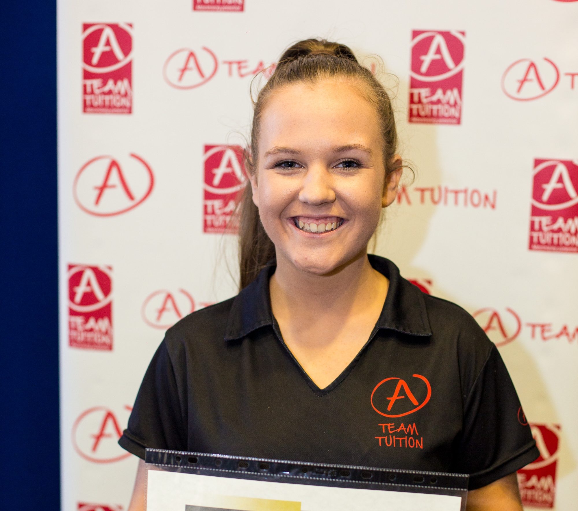 Young, smiling Gold Coast tutor holding her tutoring resources